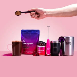 Open pouch of Spacegoods Rainbow Dust Chocolate next to metal mug and scoop.